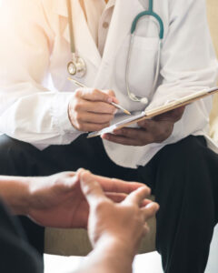 Close up of doctor completing forms while consulting with a patient