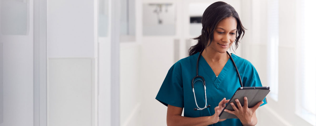 Female doctor wearing scrubs looking at a tablet