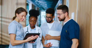 Group of young medical professionals reviewing charts together in a hospital hallway