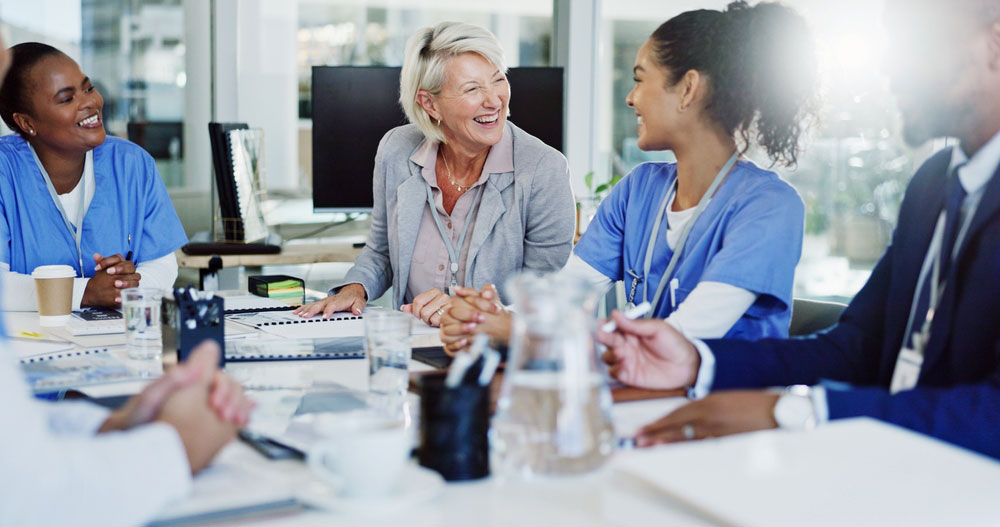 Hospital manager meeting with staff in conference room they are smiling