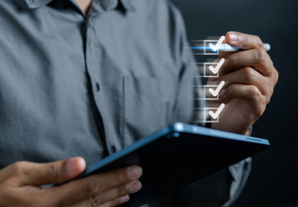 Close up of person holding tablet completing a checklist