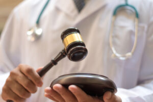 Cropped view of a doctor wearing a stethoscope holding a gavel and sound block