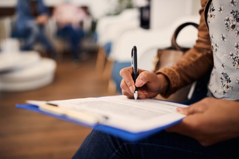 Close up of patient sitting in a waiting room filling out paperwork