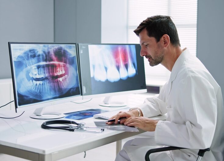 a dental expert at a desk reviewing medical records and radiology images